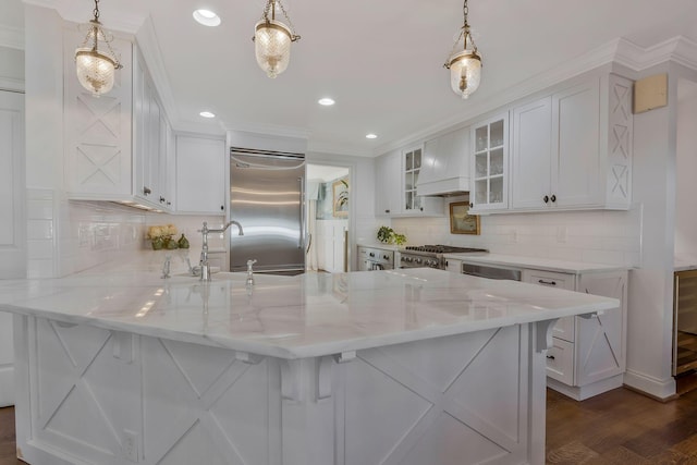 kitchen featuring premium range hood, sink, decorative light fixtures, and appliances with stainless steel finishes