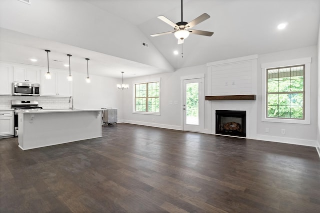 kitchen with stainless steel appliances, decorative light fixtures, a center island with sink, dark hardwood / wood-style floors, and white cabinetry