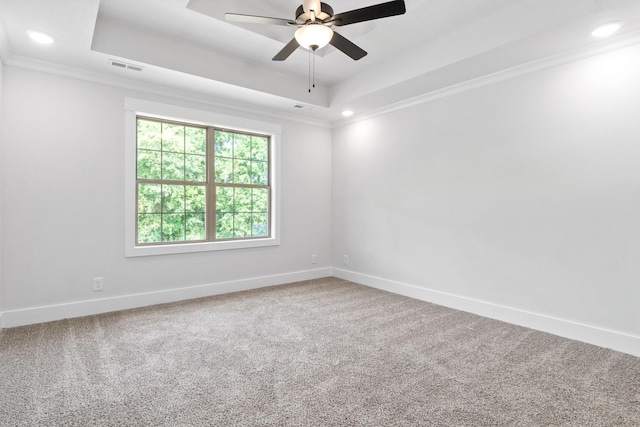 carpeted empty room with ceiling fan, crown molding, and a tray ceiling