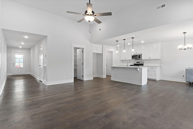 unfurnished living room featuring a high ceiling, sink, dark wood-type flooring, and ceiling fan with notable chandelier