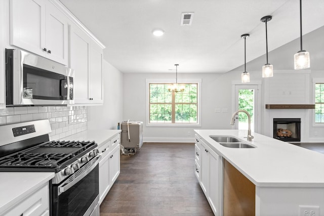 kitchen featuring pendant lighting, a center island with sink, sink, appliances with stainless steel finishes, and white cabinetry