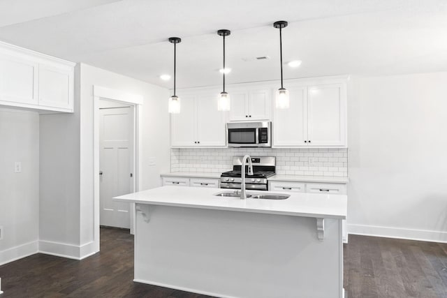 kitchen with appliances with stainless steel finishes, white cabinetry, a kitchen island with sink, and pendant lighting