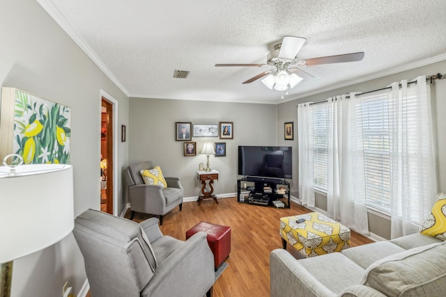 living room featuring ceiling fan, ornamental molding, a textured ceiling, and hardwood / wood-style flooring