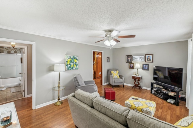 living room featuring hardwood / wood-style floors, ceiling fan, crown molding, and a textured ceiling