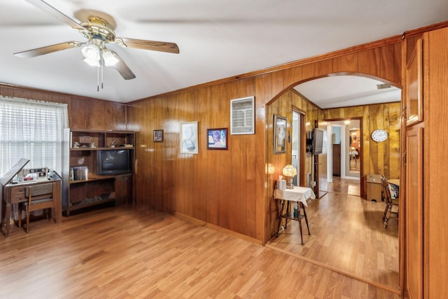 interior space with light hardwood / wood-style flooring, ceiling fan, wooden walls, and crown molding