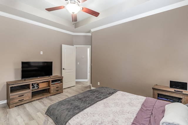 bedroom featuring a raised ceiling, ceiling fan, light hardwood / wood-style floors, and ornamental molding