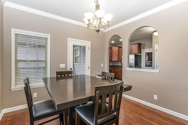 dining space featuring dark hardwood / wood-style floors, an inviting chandelier, and ornamental molding