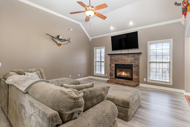 living room featuring ceiling fan, light wood-type flooring, vaulted ceiling, a fireplace, and ornamental molding