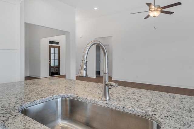 interior details with ceiling fan, light stone counters, a sink, and recessed lighting