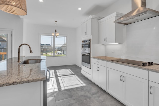 kitchen with decorative light fixtures, black electric cooktop, ventilation hood, white cabinetry, and a sink