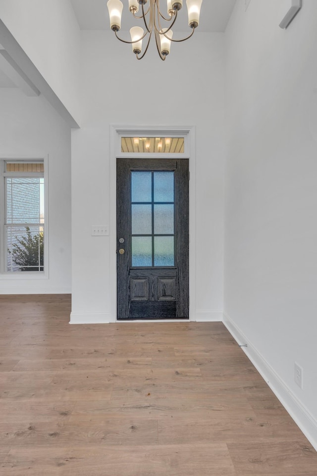 entryway featuring an inviting chandelier, light wood-style flooring, and baseboards