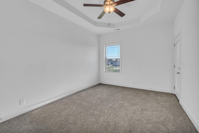 empty room with visible vents, baseboards, a raised ceiling, ceiling fan, and carpet floors