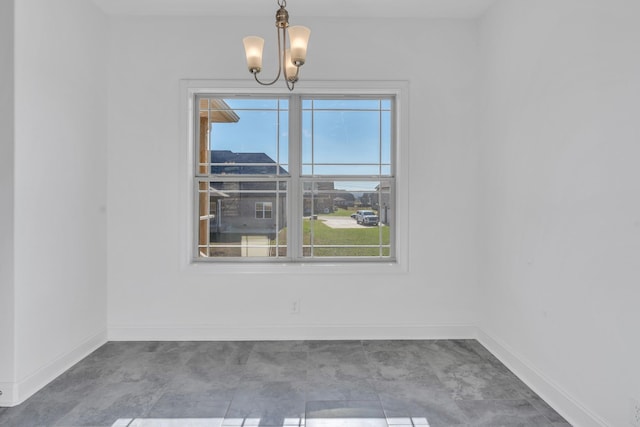 spare room with baseboards and a notable chandelier