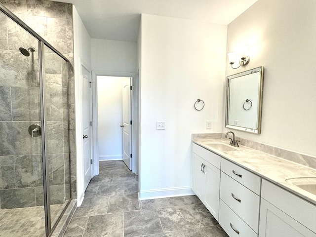 bathroom with double vanity, a shower stall, baseboards, and a sink