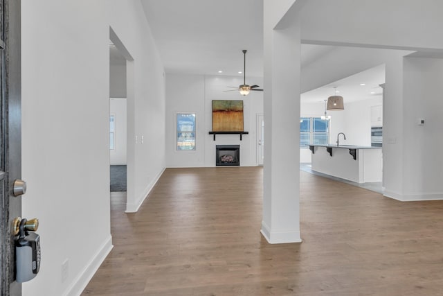 entrance foyer featuring a ceiling fan, a large fireplace, light wood-style flooring, and baseboards