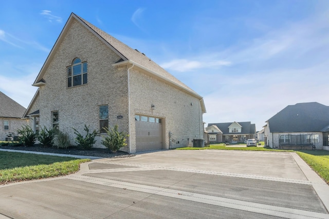 view of property exterior with central AC, brick siding, a yard, driveway, and a residential view