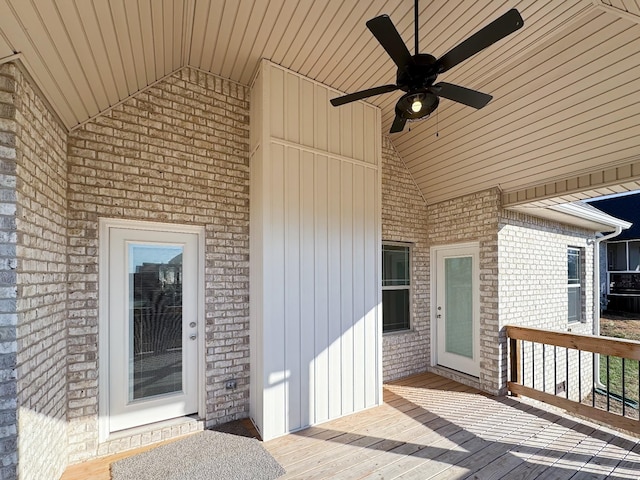 view of exterior entry with brick siding, ceiling fan, and a wooden deck