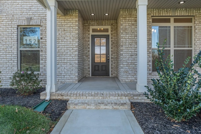 entrance to property featuring covered porch and brick siding