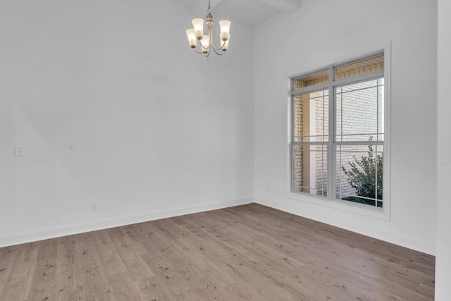 unfurnished room featuring baseboards, a chandelier, and wood finished floors