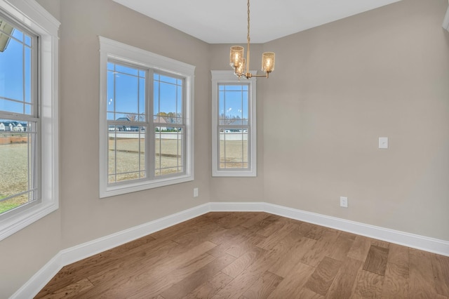 unfurnished dining area featuring a notable chandelier and hardwood / wood-style floors