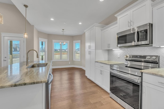 kitchen with sink, pendant lighting, white cabinets, and stainless steel appliances