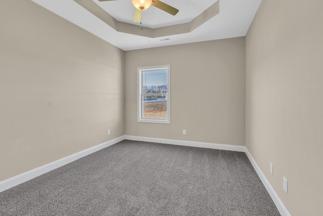 unfurnished room featuring ceiling fan, carpet floors, and a tray ceiling