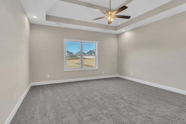 carpeted spare room with ceiling fan and a tray ceiling