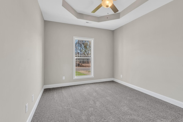 spare room featuring ceiling fan, carpet, and a tray ceiling