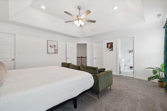 carpeted bedroom with ceiling fan, a raised ceiling, and connected bathroom