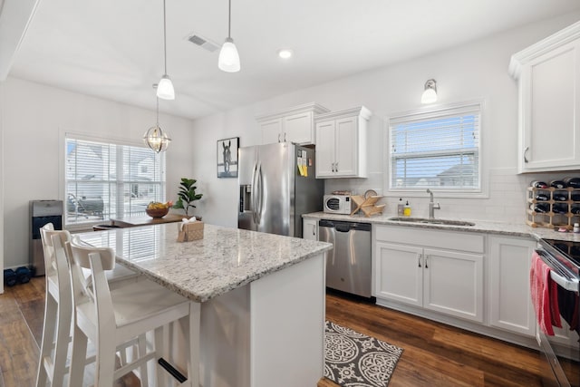 kitchen featuring white cabinetry, sink, decorative light fixtures, and appliances with stainless steel finishes