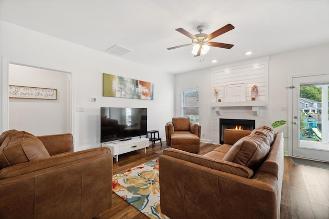 living room with a fireplace, dark hardwood / wood-style flooring, and ceiling fan