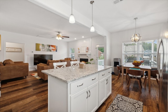 kitchen with white cabinets, a center island, hanging light fixtures, and a fireplace