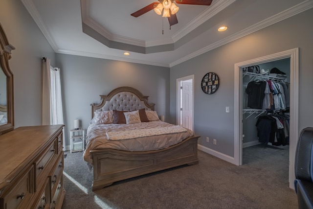 bedroom with a walk in closet, dark carpet, ornamental molding, ceiling fan, and a closet