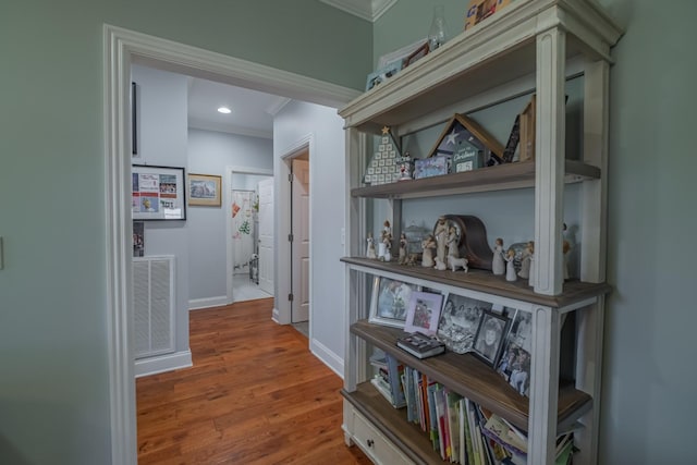 hallway with visible vents, baseboards, wood finished floors, and crown molding