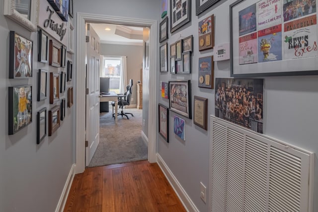 hallway featuring visible vents, crown molding, dark wood-type flooring, and baseboards