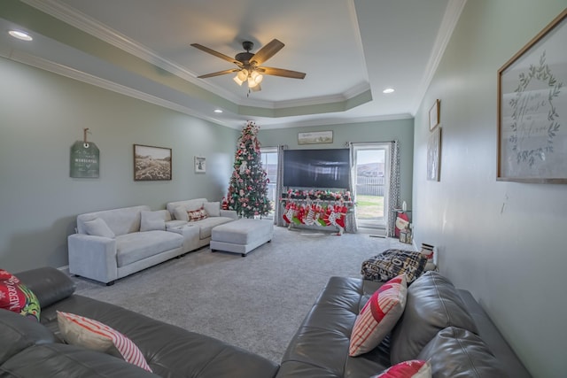 carpeted living room with ceiling fan, ornamental molding, and a tray ceiling