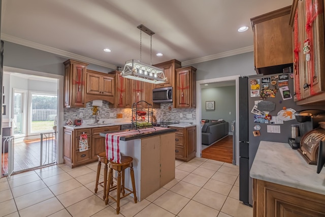 kitchen with appliances with stainless steel finishes, crown molding, sink, decorative light fixtures, and light hardwood / wood-style flooring