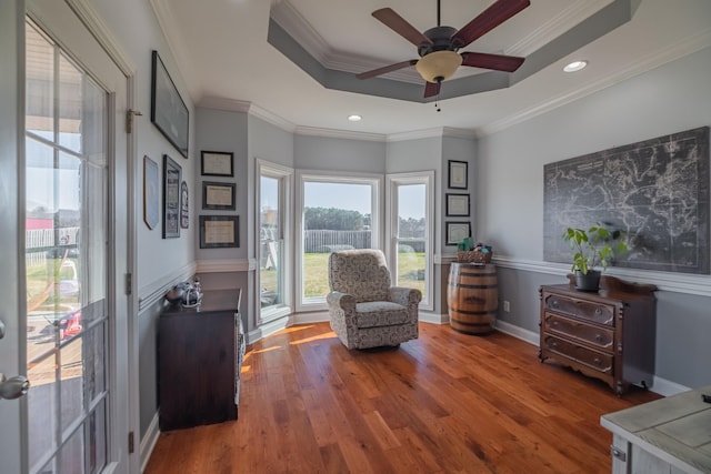 sitting room featuring crown molding, a raised ceiling, baseboards, and wood finished floors