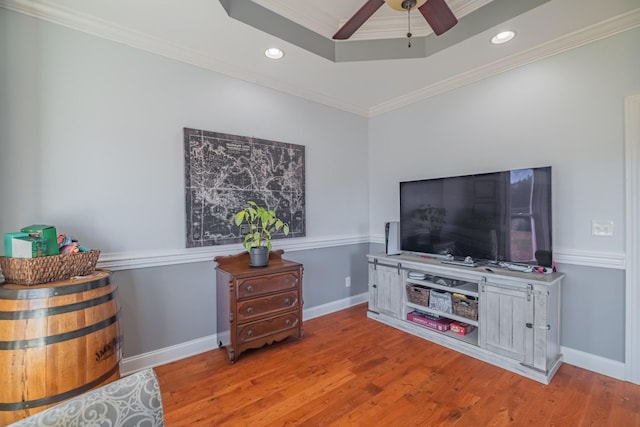 sitting room featuring baseboards, light wood-style flooring, recessed lighting, crown molding, and a raised ceiling