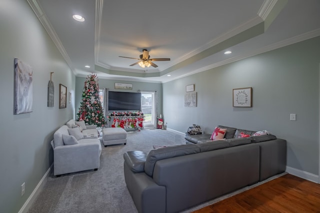 living room with hardwood / wood-style flooring, ceiling fan, ornamental molding, and a tray ceiling