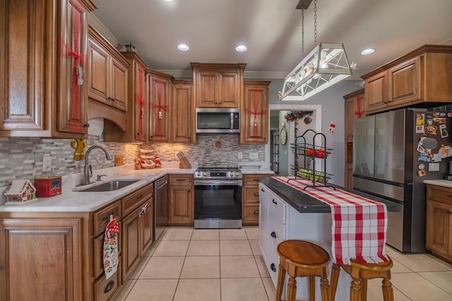 kitchen with a sink, appliances with stainless steel finishes, brown cabinetry, and light tile patterned floors