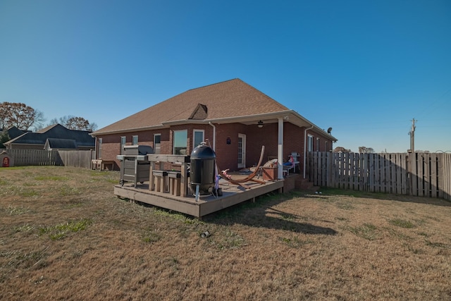 back of property featuring a yard, a fenced backyard, brick siding, and a wooden deck