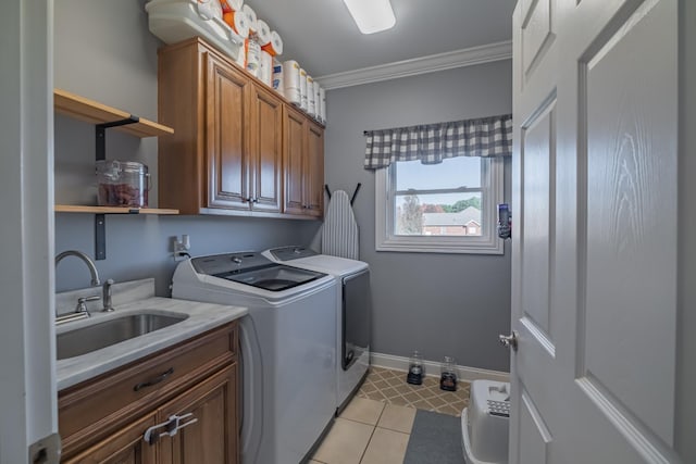 laundry area featuring ornamental molding, a sink, washer and dryer, cabinet space, and baseboards