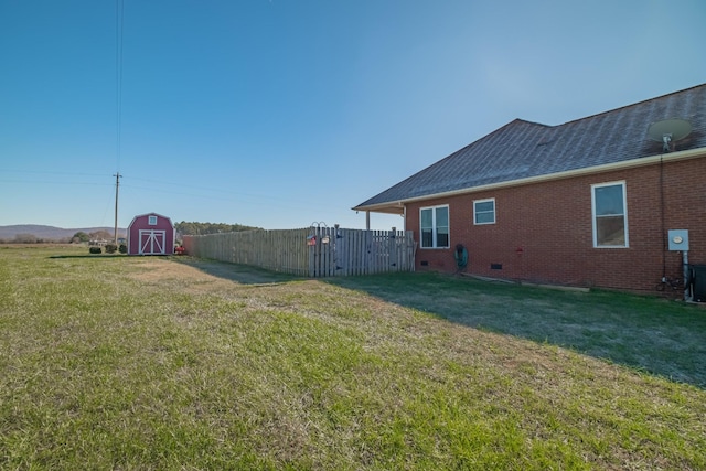 view of yard with an outbuilding, a storage unit, and fence