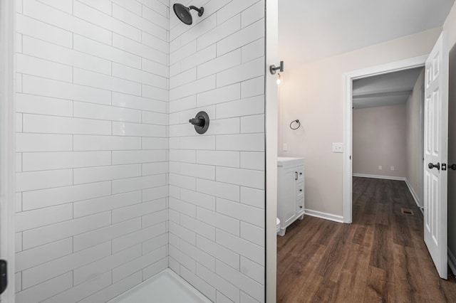 bathroom with tiled shower, wood-type flooring, and vanity