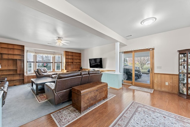 living room featuring hardwood / wood-style flooring, a wealth of natural light, wooden walls, and ceiling fan