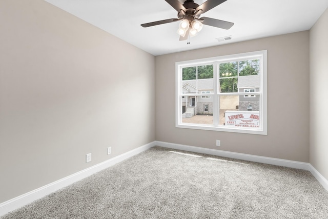 carpeted empty room with a ceiling fan, visible vents, and baseboards