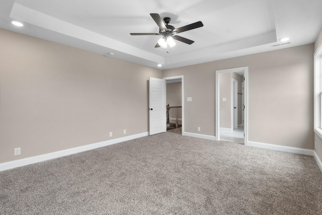 unfurnished bedroom with carpet floors, a raised ceiling, and ceiling fan