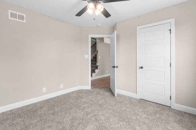 unfurnished bedroom featuring baseboards, a ceiling fan, visible vents, and light colored carpet