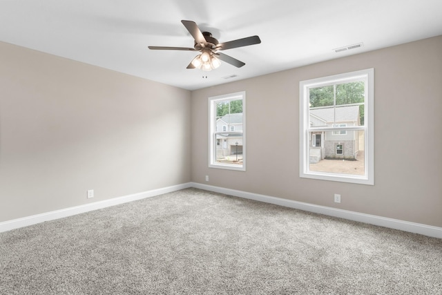 carpeted spare room featuring a ceiling fan, visible vents, and baseboards